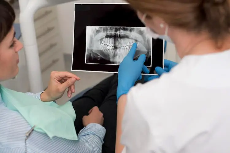 dentista mostrando una radiografía de una boca con dientes supernumerarios 