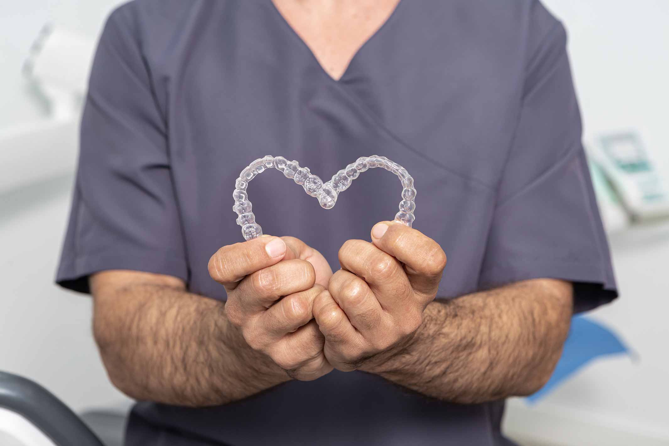 Hombre haciendo un corazón con alineadores dentales transparentes