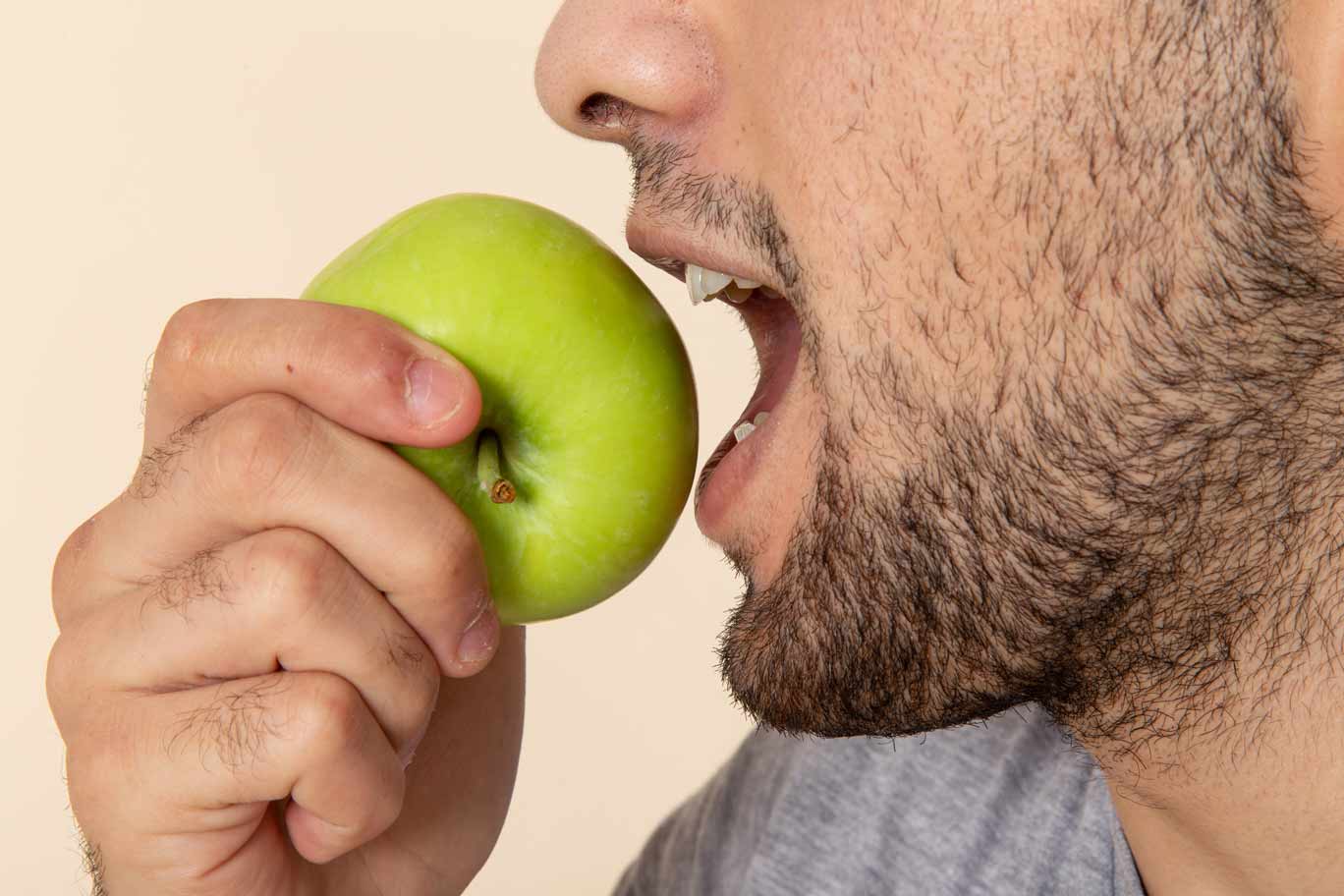 Hombre de perfil comiendo una manzana