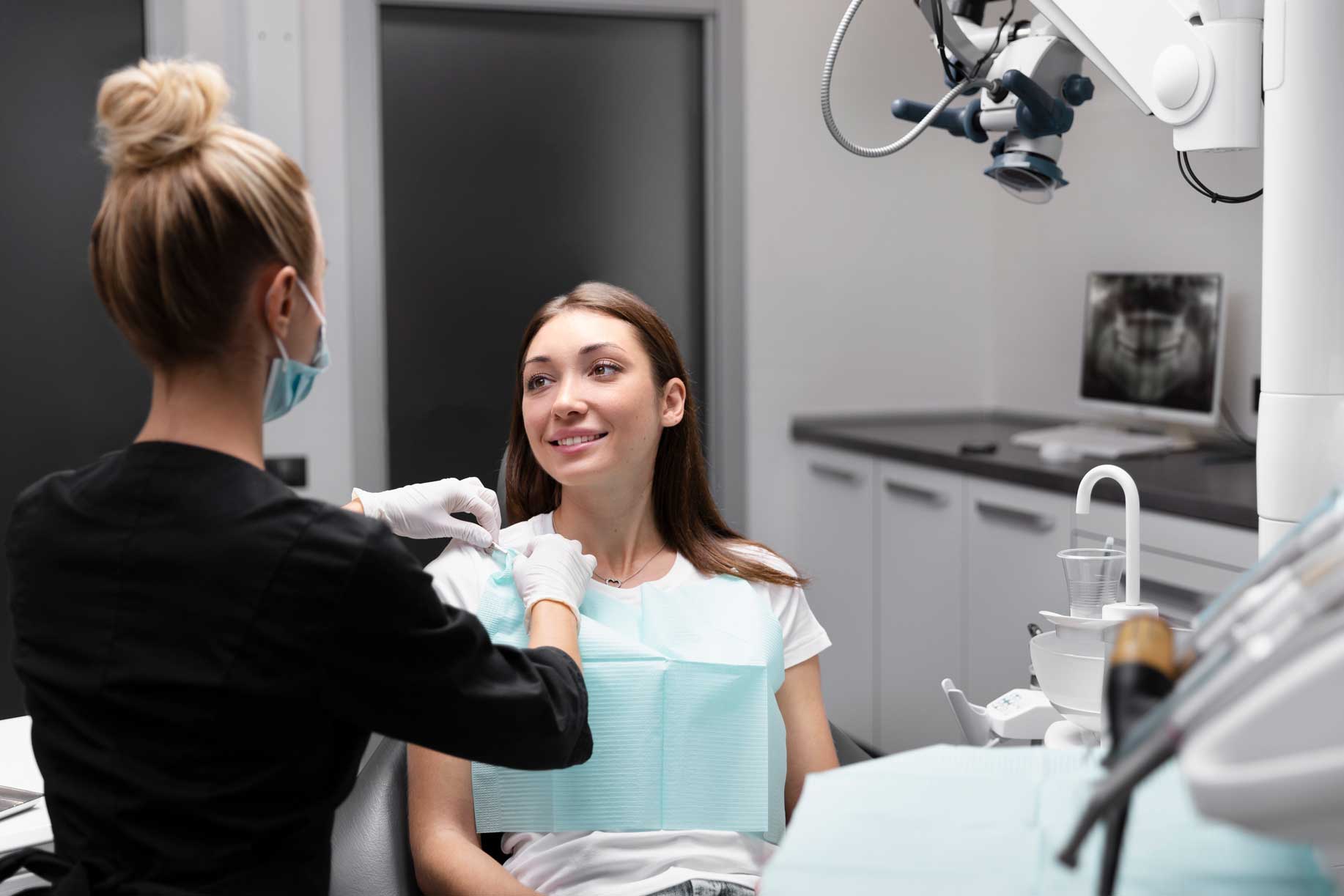 Dentista colocando a una paciente en consulta para explicarle qué es una endodoncia. 